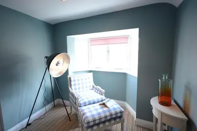 a room with a chair and a lamp and a window at Bunny Cottage, Aldeburgh in Aldeburgh