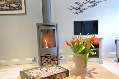 a fireplace in a living room with a vase of flowers at Bunny Cottage, Aldeburgh in Aldeburgh