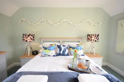 a bedroom with a white bed with two lamps at Bunny Cottage, Aldeburgh in Aldeburgh