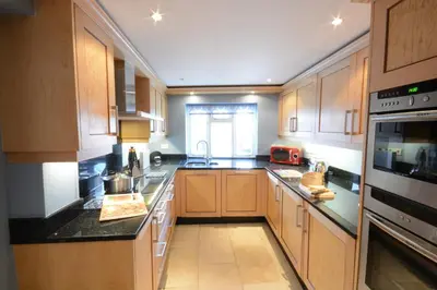 a large kitchen with wooden cabinets and a window at Bunny Cottage, Aldeburgh in Aldeburgh