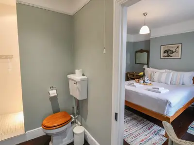a bedroom with a bed and a toilet with a wooden seat at Lavender House, Aldeburgh in Aldeburgh