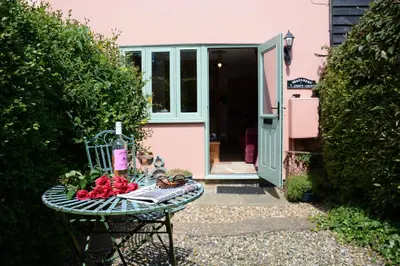 a table with fruit on it in front of a pink house at Seafarers in Fressingfield