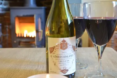 a bottle of wine sitting next to a glass at Pebble Beach Cottage, Aldeburgh in Aldeburgh