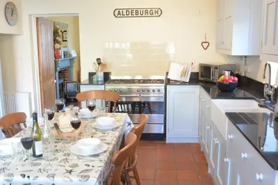a kitchen with a table with glasses of wine at Pebble Beach Cottage, Aldeburgh in Aldeburgh