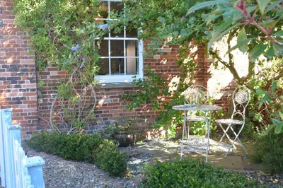 a table and two chairs in front of a brick building at Pebble Beach Cottage, Aldeburgh in Aldeburgh