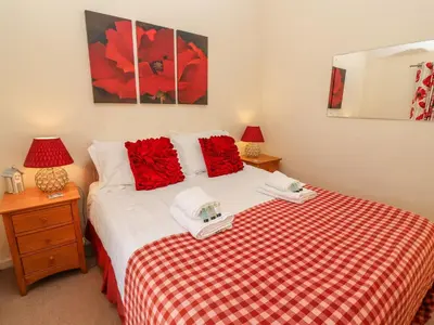 a bedroom with a red and white bed with two lamps at Winkle Cottage, Aldeburgh in Aldeburgh
