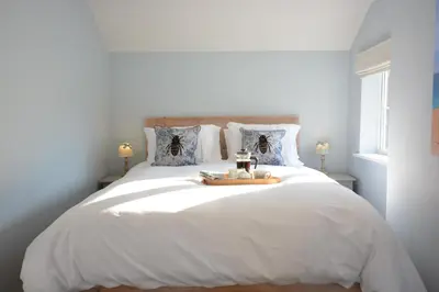 a bedroom with a white bed with a tray on it at Little Turnpike Cottage, Melton in Woodbridge