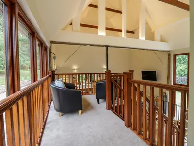 a room with a balcony with chairs and a tv at Quill Farm Barn in Campsea Ashe