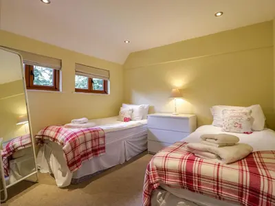 a bedroom with two beds and a mirror at Quill Farm Barn in Campsea Ashe