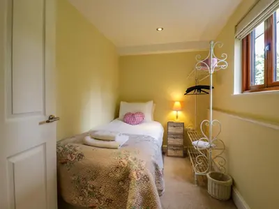 a small bedroom with a bed and a window at Quill Farm Barn in Campsea Ashe