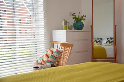 a bedroom with a bed with a chair and a window at Aldeburgh Lodge Gardens in Aldeburgh