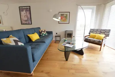 a living room with a blue couch and a glass table at Aldeburgh Lodge Gardens in Aldeburgh