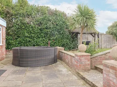 a garden with a brick wall and a palm tree at Little Wissett, Aldeburgh in Aldeburgh