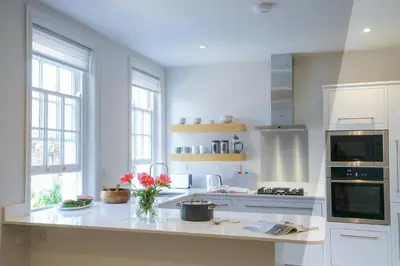 a white kitchen with a vase of flowers on a counter at 10 Church Walk, Aldeburgh in Aldeburgh