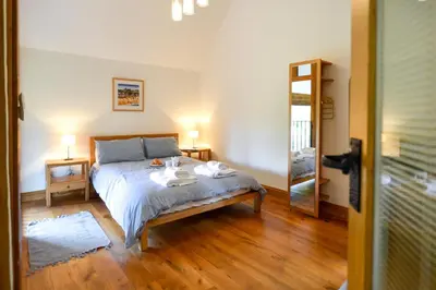 a bedroom with a bed and a mirror at Two Chantry Barns, Orford in Orford