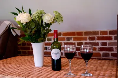 two glasses of red wine and a vase of flowers at Two Chantry Barns, Orford in Orford