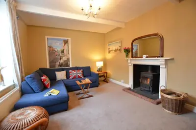 a living room with a blue couch and a fireplace at Gosfield Cottage, Aldeburgh in Aldeburgh