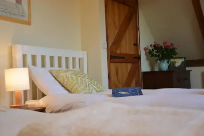 two beds in a bedroom with a book on them at Wheelwright's Barn in Halesworth