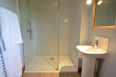 a bathroom with a glass shower and a sink at Wheelwright's Barn in Halesworth