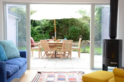 a living room with a blue couch and a table with an umbrella at 2 Pink Cottages, Aldeburgh in Aldeburgh