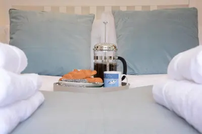 a bed with a blender and a plate of food at 2 Pink Cottages, Aldeburgh in Aldeburgh