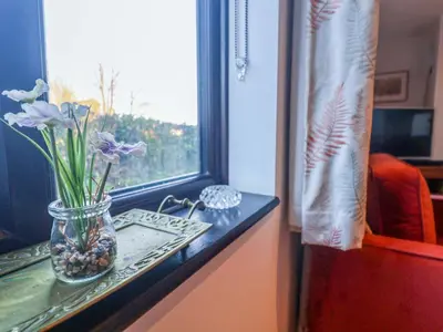 a vase with purple flowers sitting on a window sill at Pine Cottage in Woodbridge