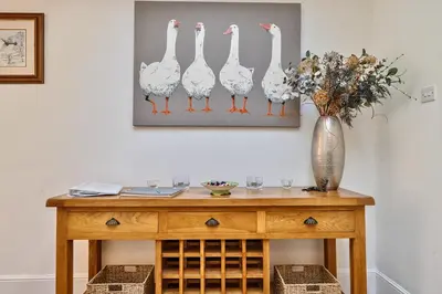 a wooden table with a vase of flowers and a vase at Bedingfield House, nr Debenham in Debenham