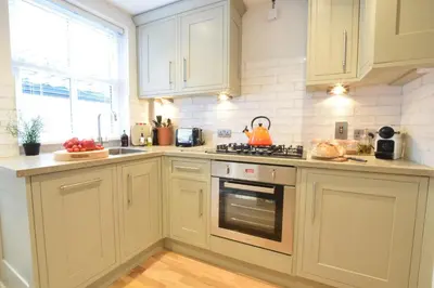 a kitchen with white cabinets and a stove top oven at 53 Tern Cottage, Aldeburgh in Aldeburgh