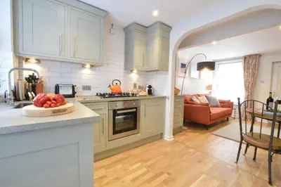 a kitchen with white cabinets and a bowl of fruit on a counter at 53 Tern Cottage, Aldeburgh in Aldeburgh