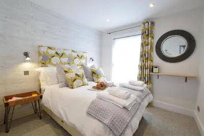 a bedroom with a large bed with a mirror at 53 Tern Cottage, Aldeburgh in Aldeburgh