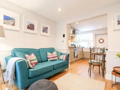 a living room with a blue couch and a kitchen at 51 Tern Cottage, Aldeburgh in Aldeburgh