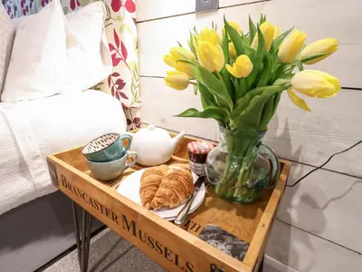 a tray with a vase of flowers and croissants on a table at 51 Tern Cottage, Aldeburgh in Aldeburgh