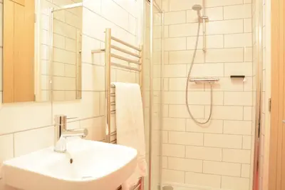 a white bathroom with a sink and a shower at Mellows, Thorpeness in Thorpeness