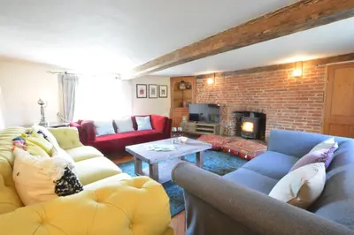 a living room with couches and a brick wall at The White House with Studio in Homersfield