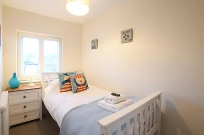 a bedroom with a white bed and a window at Smugglers Rest, Aldeburgh in Aldeburgh