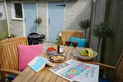 a table with a bottle of wine and a bowl of fruit at Smugglers Rest, Aldeburgh in Aldeburgh
