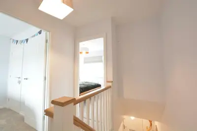 a room with a staircase and a mirror at Lapwings, Aldeburgh in Aldeburgh