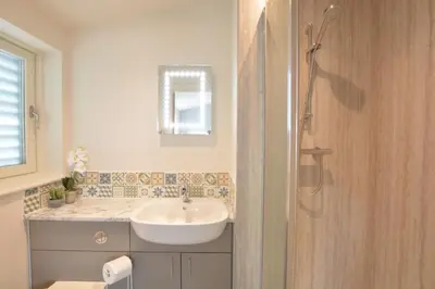 a white bathroom with a sink and a shower at Bramertons Nest, Long Melford in Long Melford