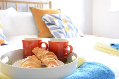 a bowl with two cups and two croissants on a bed at Bramertons Nest, Long Melford in Long Melford