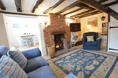 a living room with blue couches and a brick fireplace at The Moorings, Orford in Orford