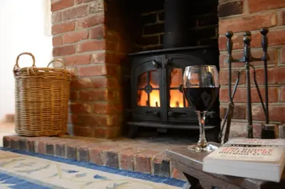 a glass of wine in front of a fireplace at The Moorings, Orford in Orford