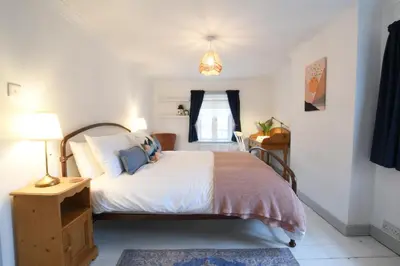 a bedroom with a bed with white sheets and blue pillows at Rosedene, Rickinghall in Rickinghall