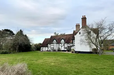 an old black and white house with a green yard at Church Farmhouse, Cookley in Halesworth
