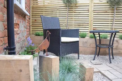 a bird statue next to a chair and a table at Arlo Cottage, Orford in Orford