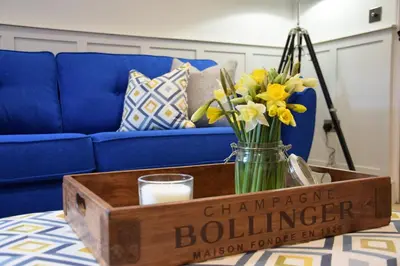 a vase of flowers on a table with a blue couch at Arlo Cottage, Orford in Orford