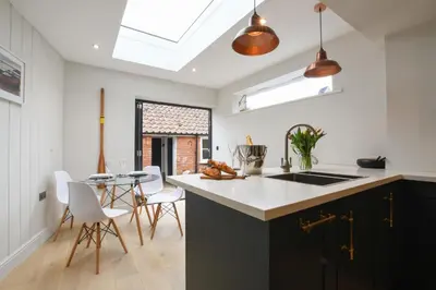 a kitchen with a sink and a table with chairs at Arlo Cottage, Orford in Orford