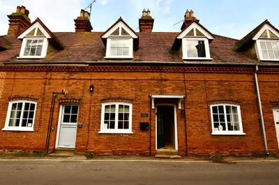 a red brick building with white windows and a door at Arlo Cottage, Orford in Orford