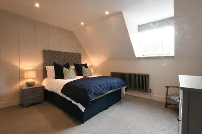 a bedroom with a bed with a blue comforter and a window at Arlo Cottage, Orford in Orford