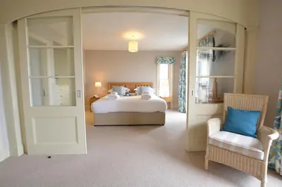 a bedroom with a bed and a chair in a room at Tamarisk, Aldeburgh in Aldeburgh