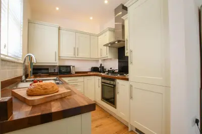 a kitchen with white cabinets and a cutting board at The Gallery, Blythburgh in Blythburgh